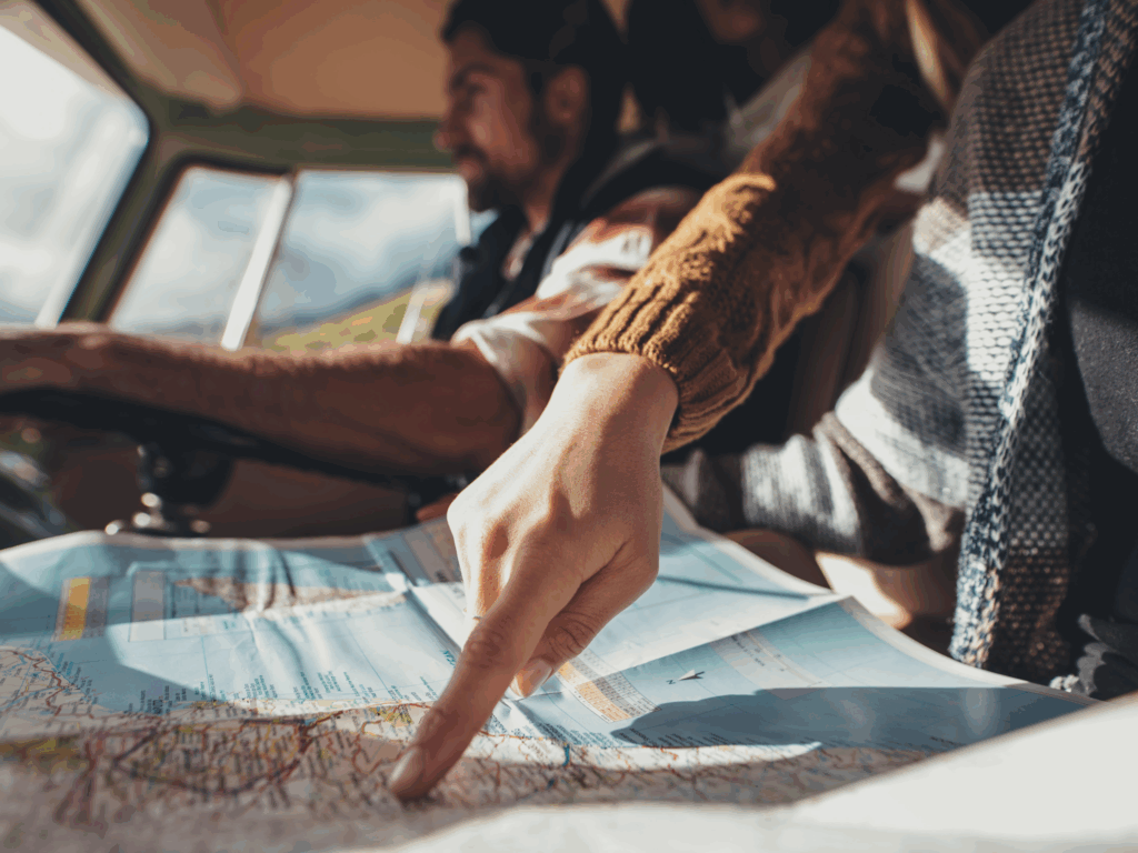 Adventurer pointing to a spot on a paper map inside a vehicle