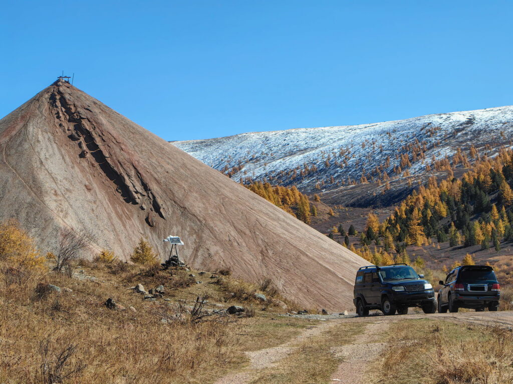 Two off-road vehicles on a dirt trail below a mountain